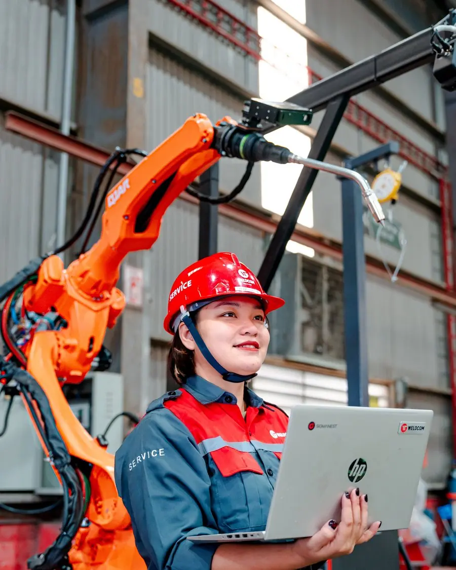 Ingeniera con su portátil junto a un robot industrial